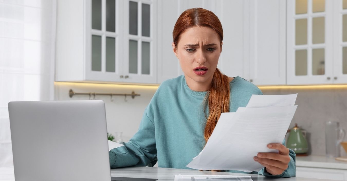 Concerned OnlyFans creator examining prorated taxes paperwork at home with a laptop.