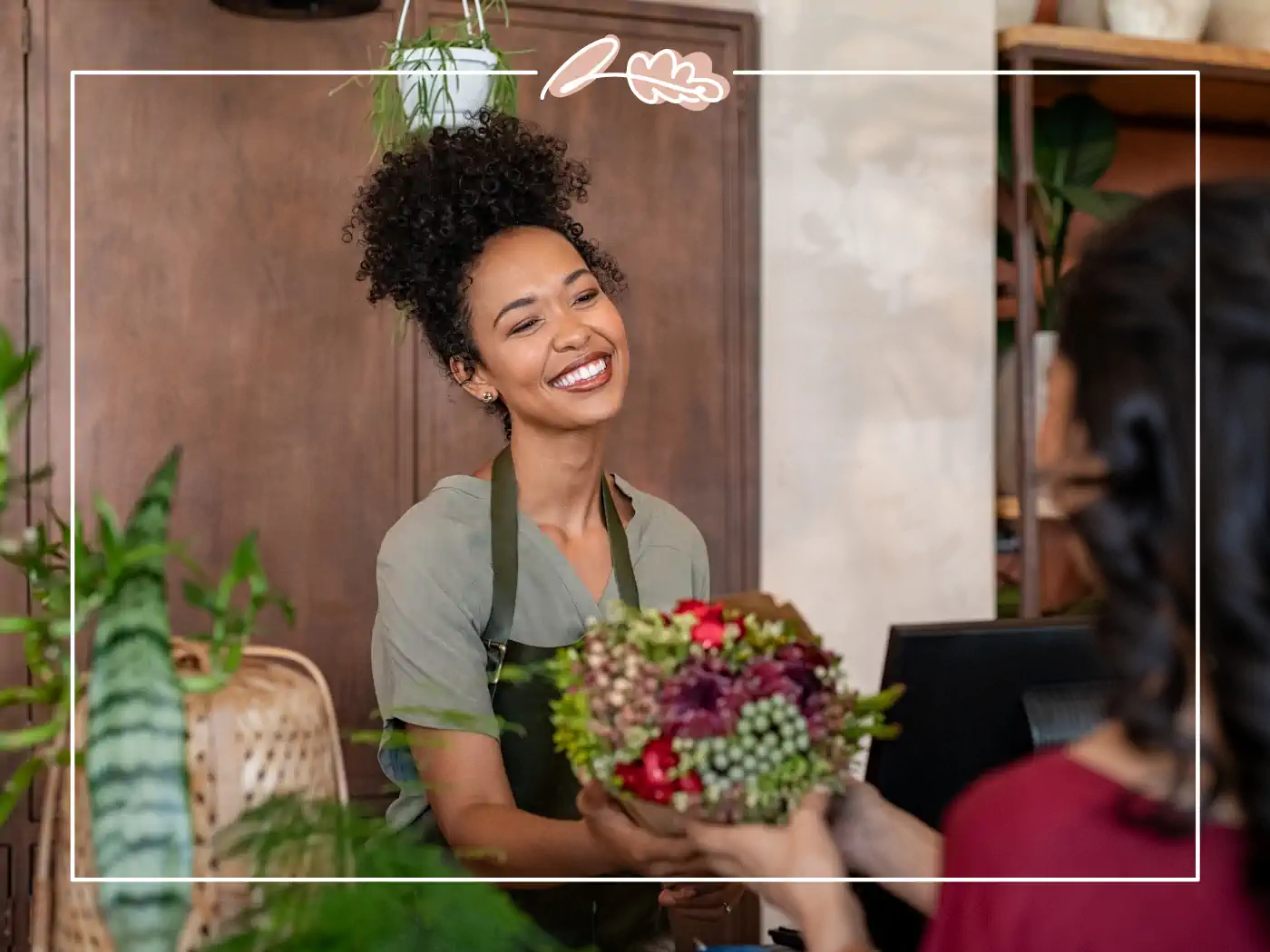 Smiling woman handing a bouquet of flowers to a customer - Fabulous Flowers and gifts