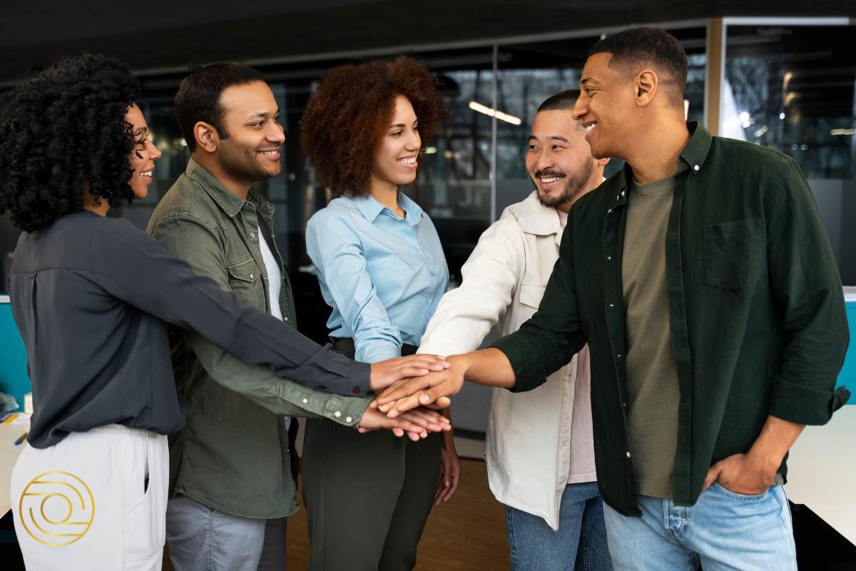 Team bonding moment, with hands joined in a group huddle, symbolising teamwork and unity in a modern office setting.