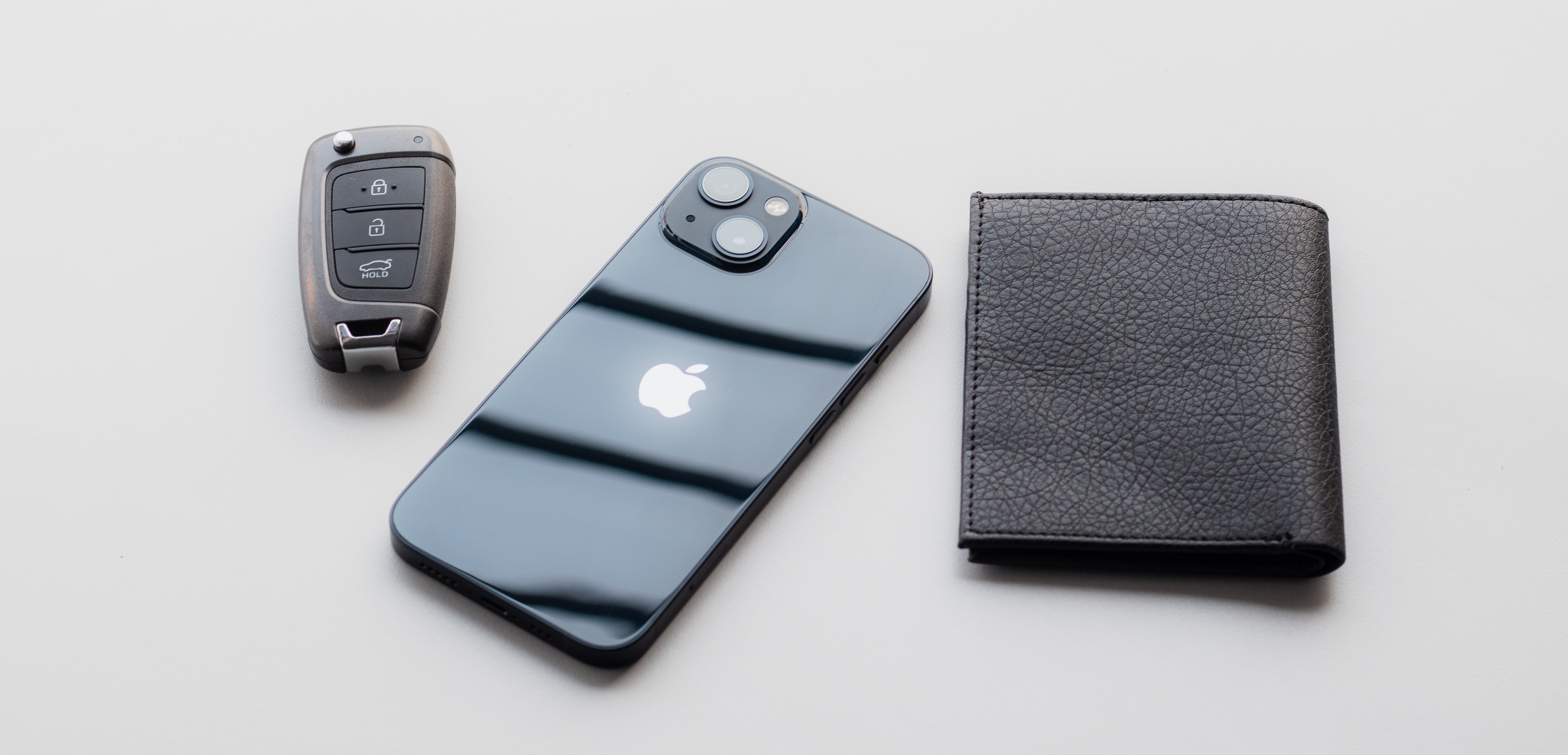 Car key fob, iphone, and wallet sitting side-by-side