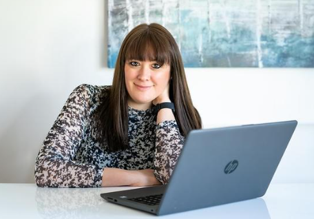Co-founder Dani sitting at white kitchen table with laptop