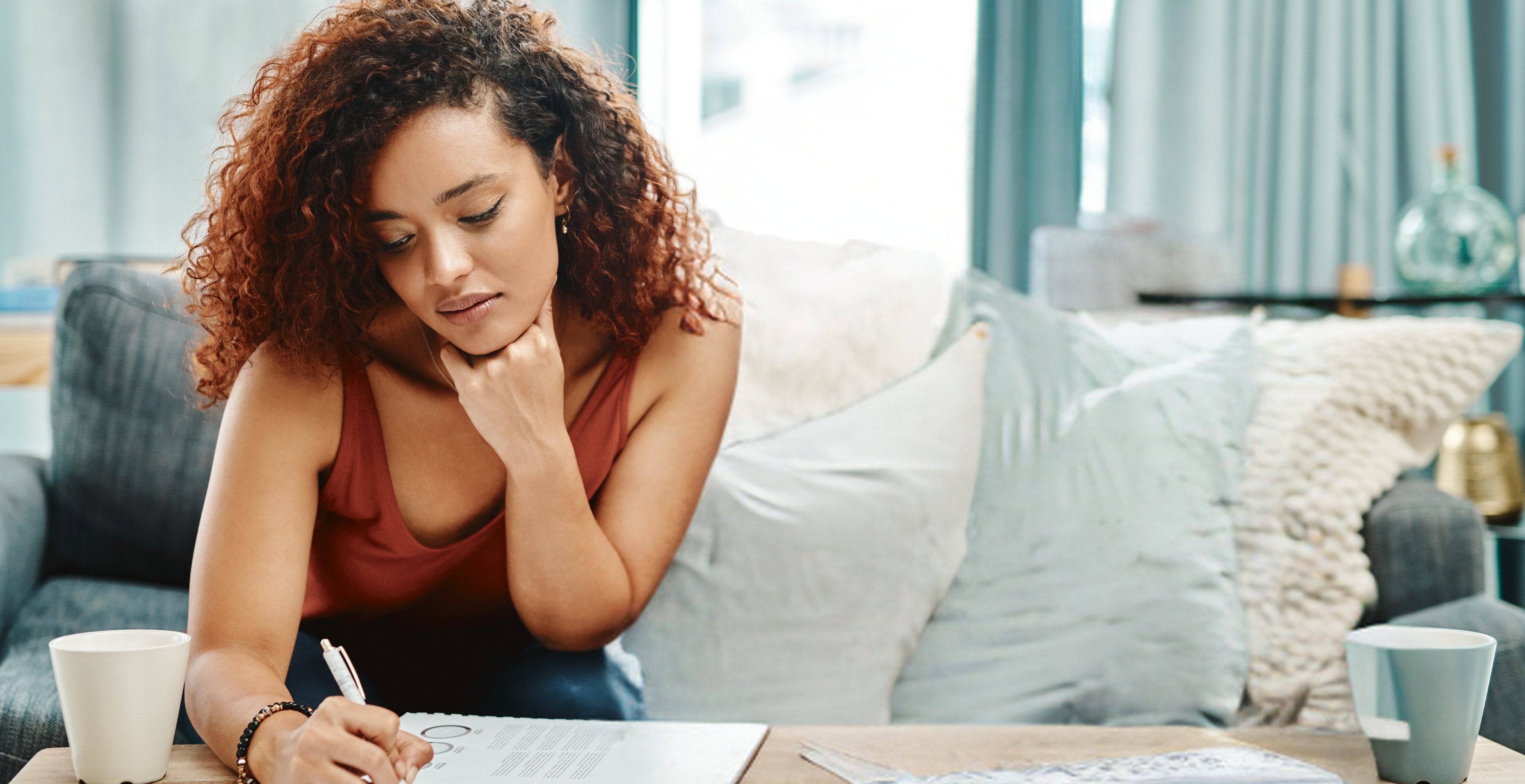 Woman in a lavender sweater writing notes, planning OnlyFans tax write offs at a desk.