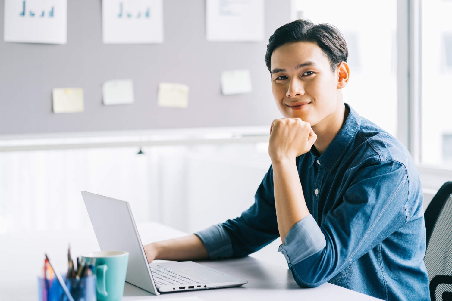 A Filipino manager smiling at his desk.