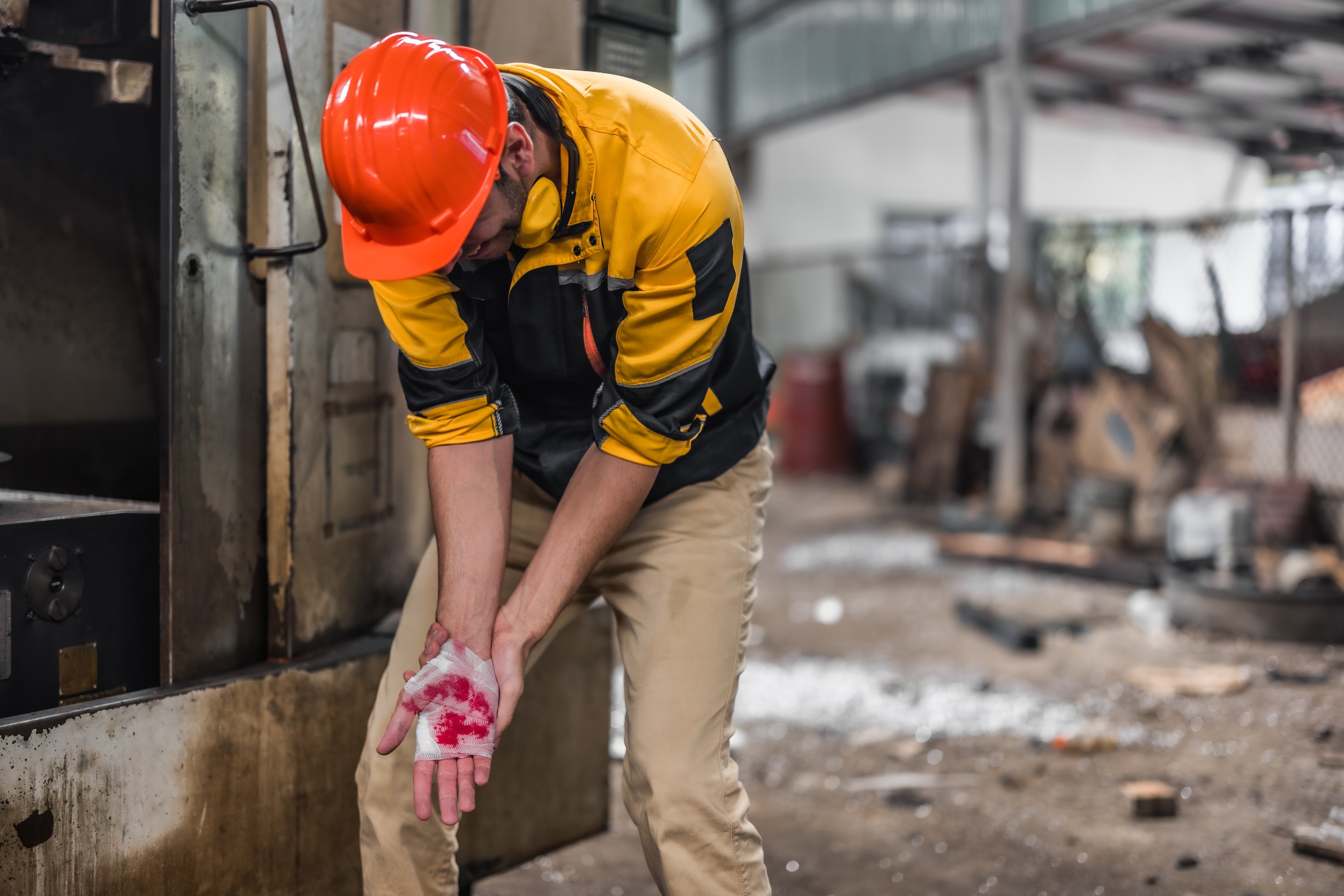 A worker stands with a bleeding hand caused by lapsed safety procedures