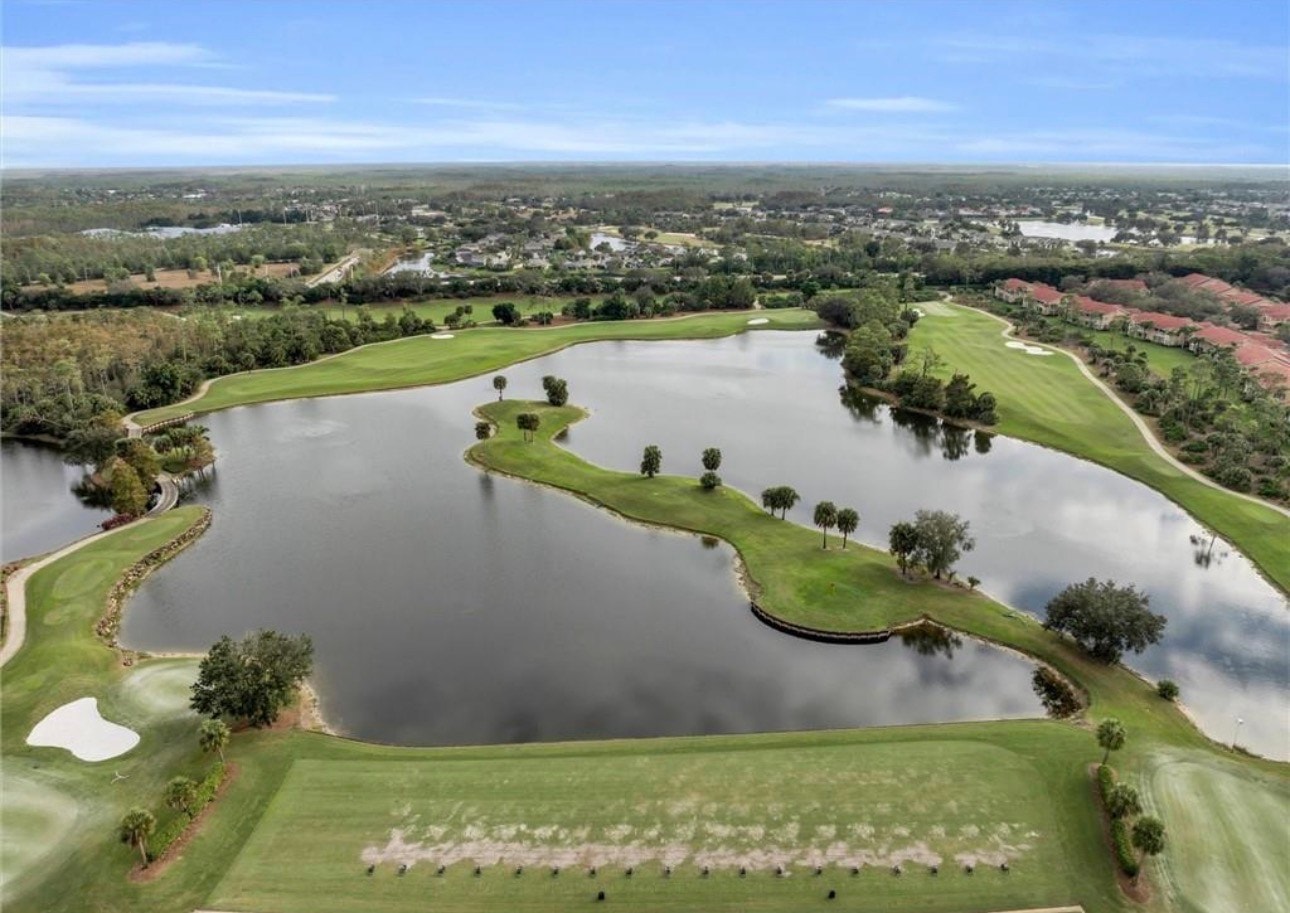 An aerial view of the Grandezza community in Estero, FL, showcases the expansive golf course, beautiful lakes, and luxury single-family homes nestled among natural preserves, highlighting the tranquil environment of this gated community. The image captures a vibrant landscape that includes amenities like tennis courts and a clubhouse, emphasizing the lifestyle and accessibility for residents.