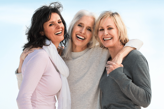 smiling group of 3 woman with their arms around each others shoulders