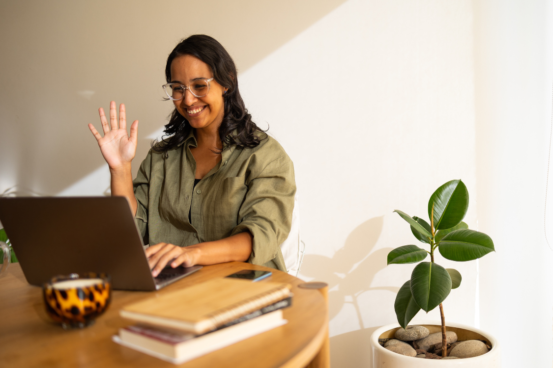 Remote Filipino team member greeting on a video call while working from home with a laptop