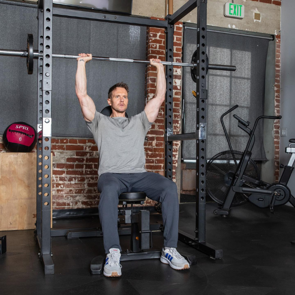 An image showing a person performing bilateral shoulder presses on a Smith machine.