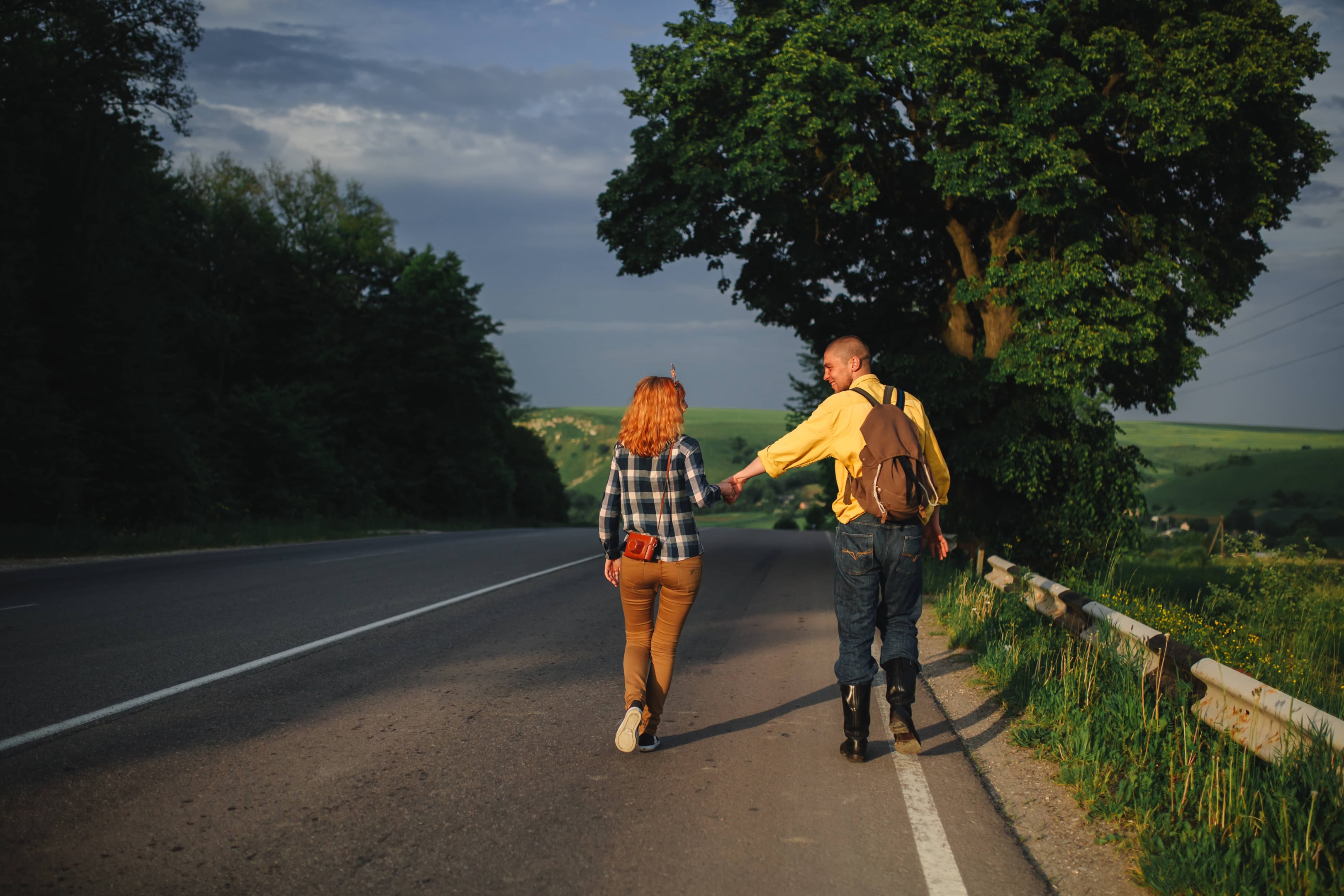 A couple walks hand in hand down a quiet country road, symbolizing the peace of mind that can come from working with trustworthy debt settlement companies.