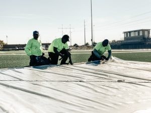 Crew performing base preparation work during running track installation.