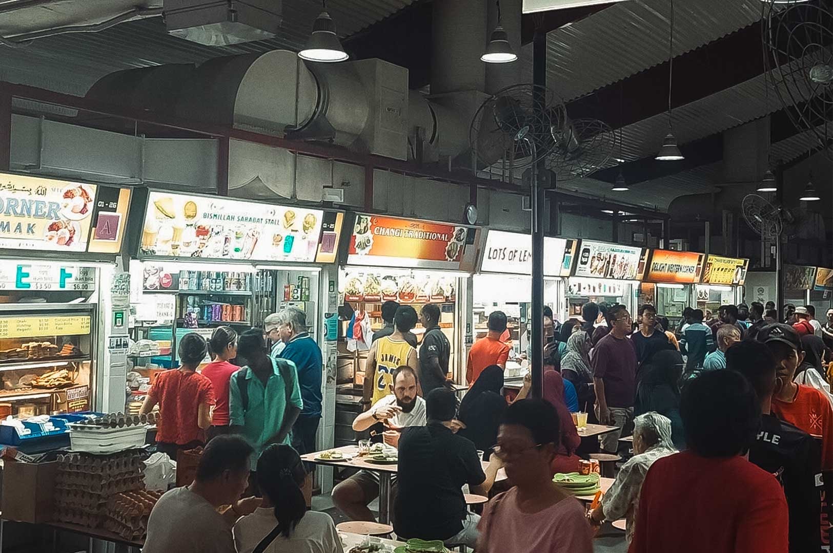 Busy Changi Village Hawker Centre with diners and food stalls during peak hours.