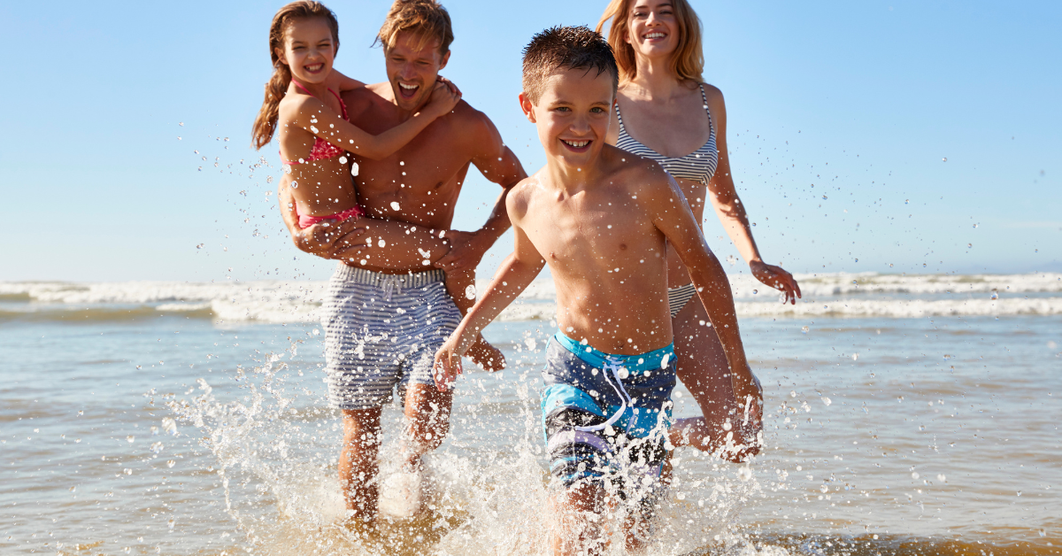 Family splashing in the waves at Ocean Grove beach, enjoying a summer vacation near Ocean Grove NJ rentals.