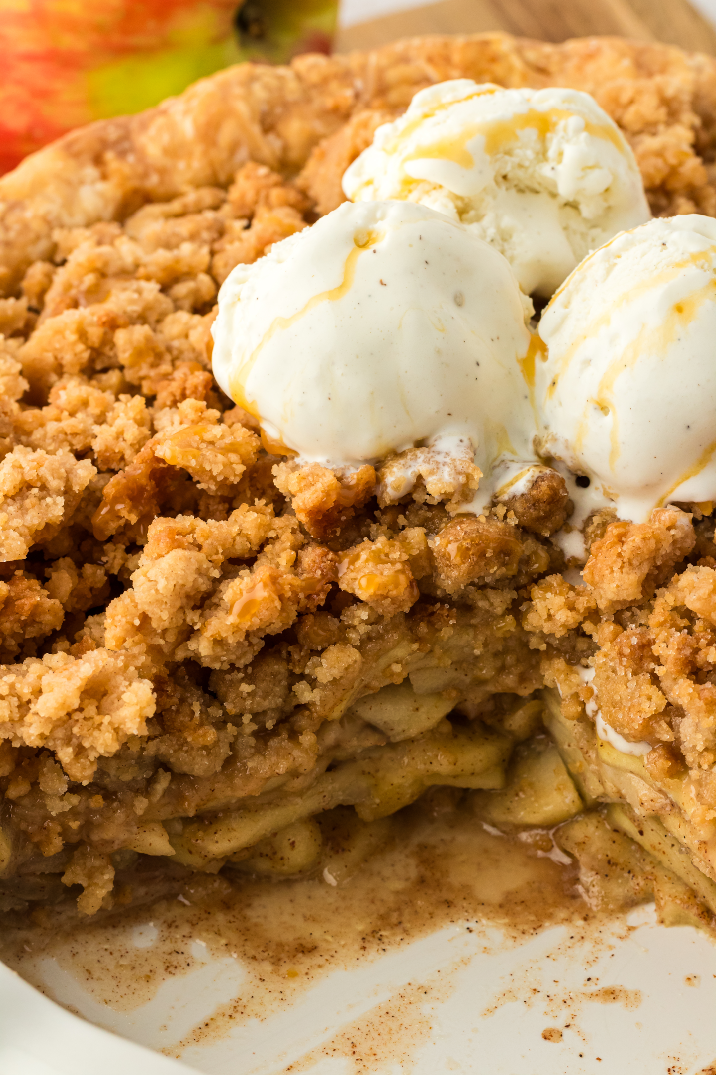 whole dutch apple pie with piece missing and topped with vanilla ice cream