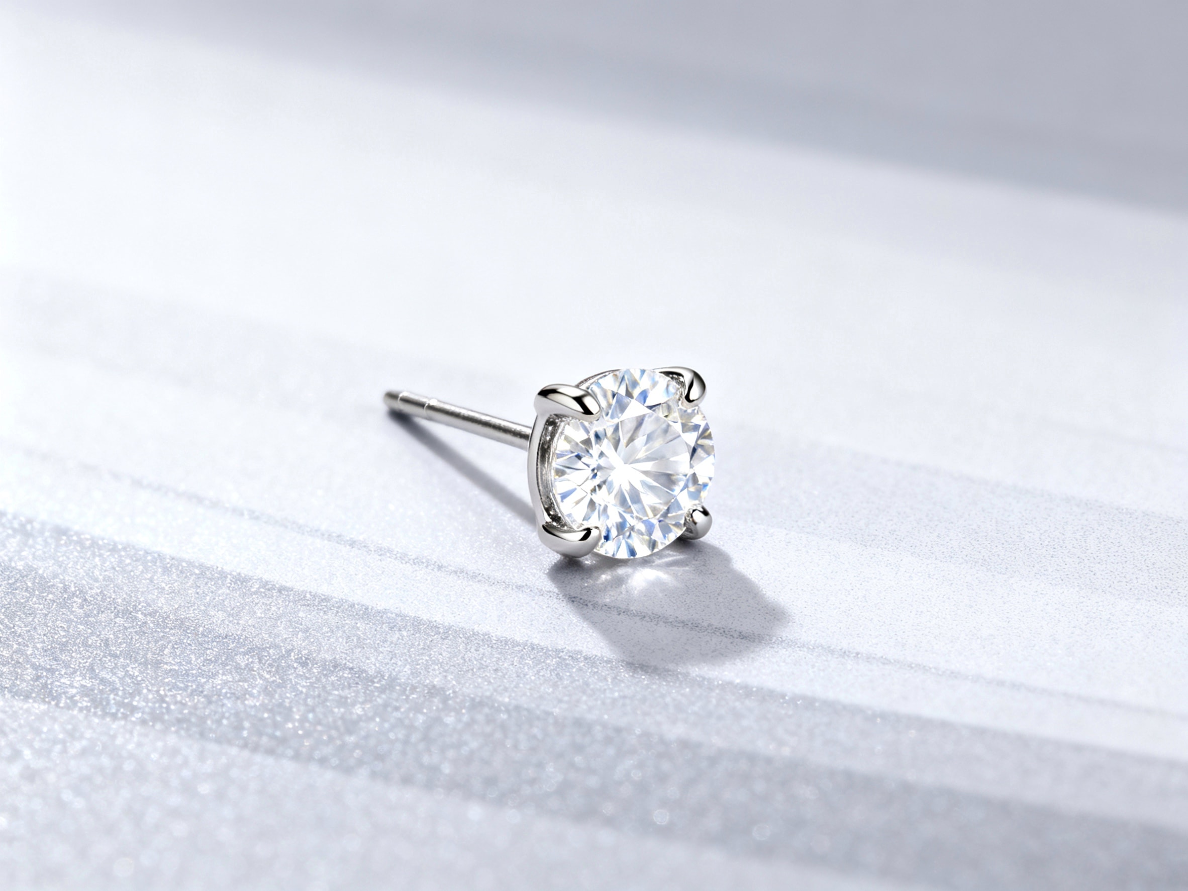 A single diamond stud earring in a four-catch setting.