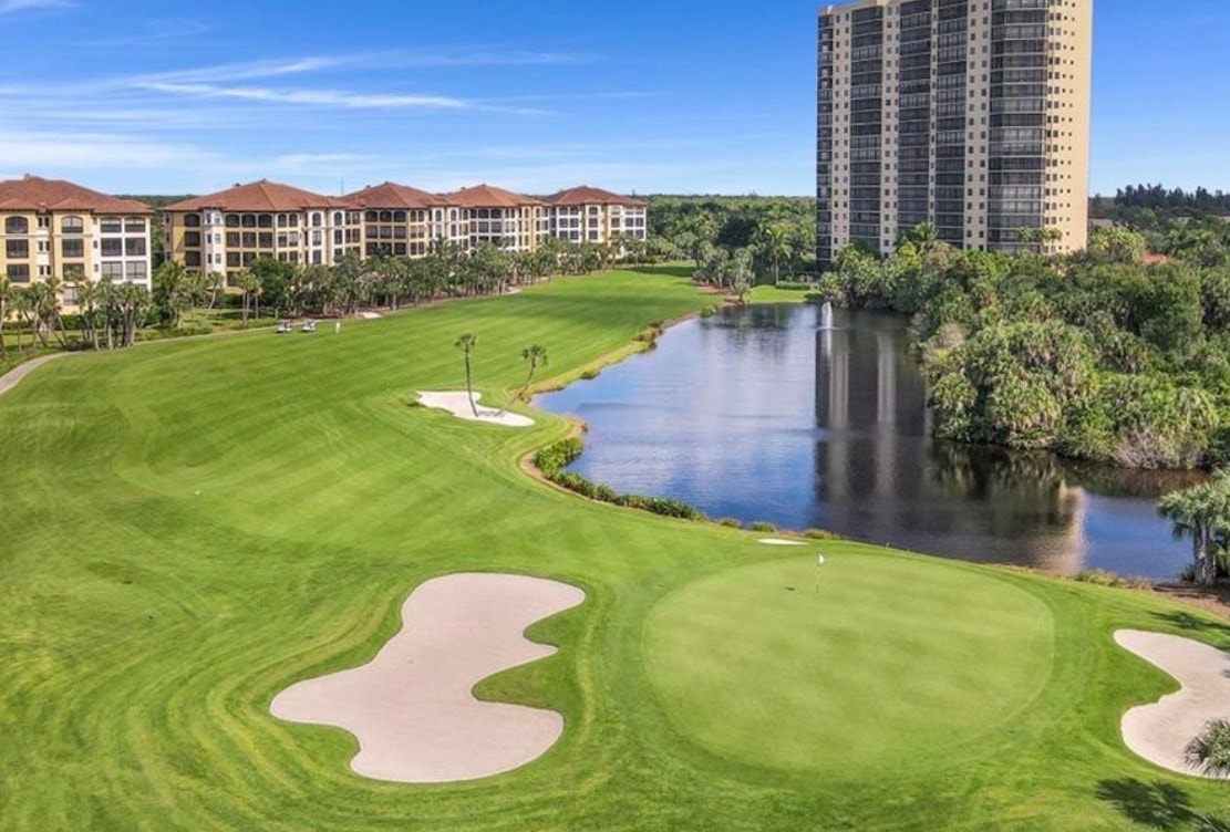 The image depicts a prestigious high-rise luxury condominium tower surrounded by palm trees, offering breathtaking waterfront views. This premier residence features world-class amenities, including a resort-style pool and private beach park access, ideal for those seeking elevated coastal living in Bonita Springs, FL.