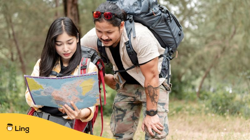 Two asian people use map for hiking in the forest