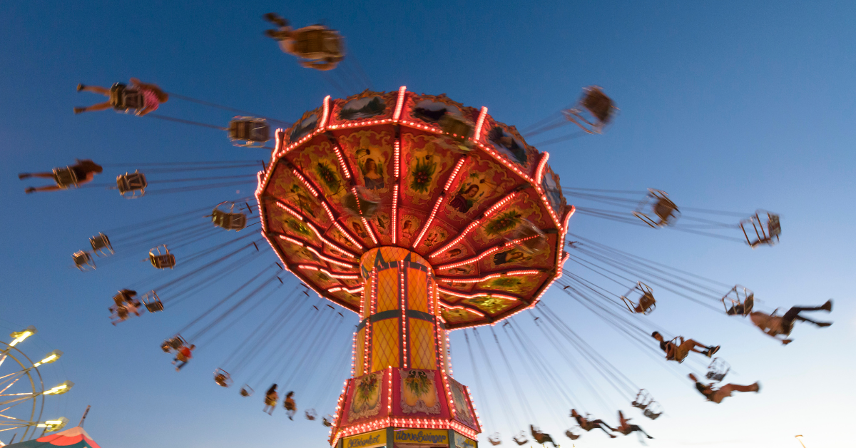 Riders soaring on a chain swing ride at dusk at a Wildwood NJ theme park, one of the many fun activities and amusement rides available at Wildwood vacation rentals on the Jersey Shore