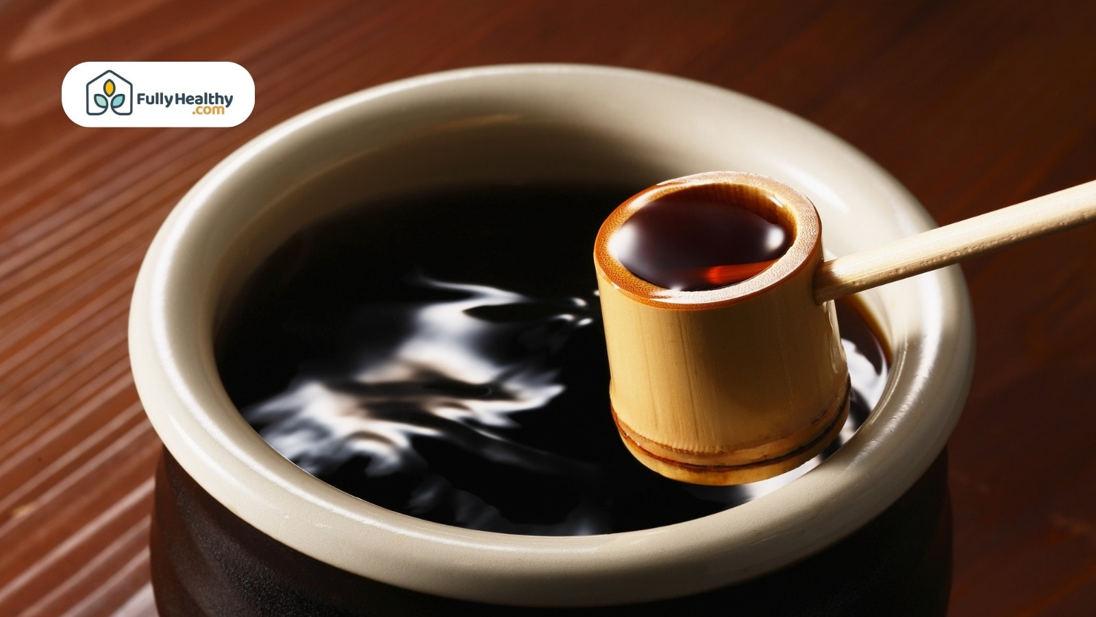 Wooden ladle dipping soy sauce from ceramic container on table