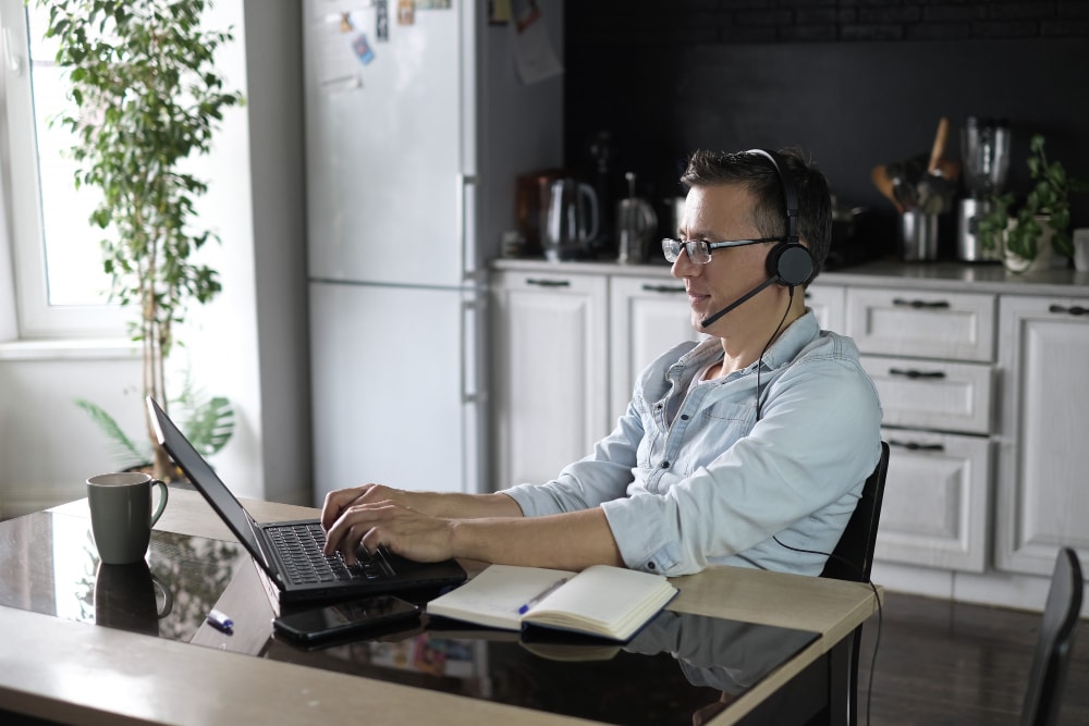 Man using laptop working online at home over an internet connection through a cloud PBX phone system.