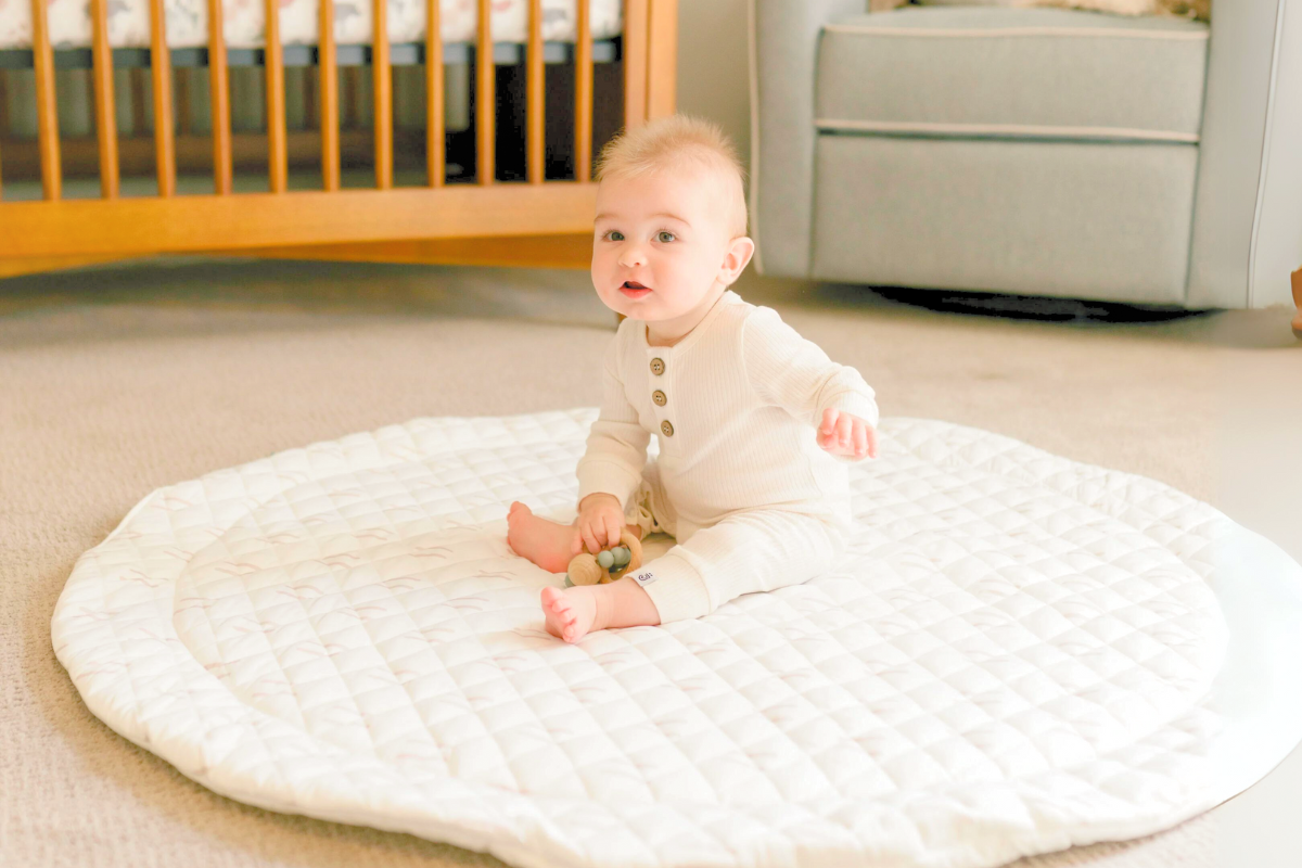 Baby sitting on play mat by Poppyseed Play