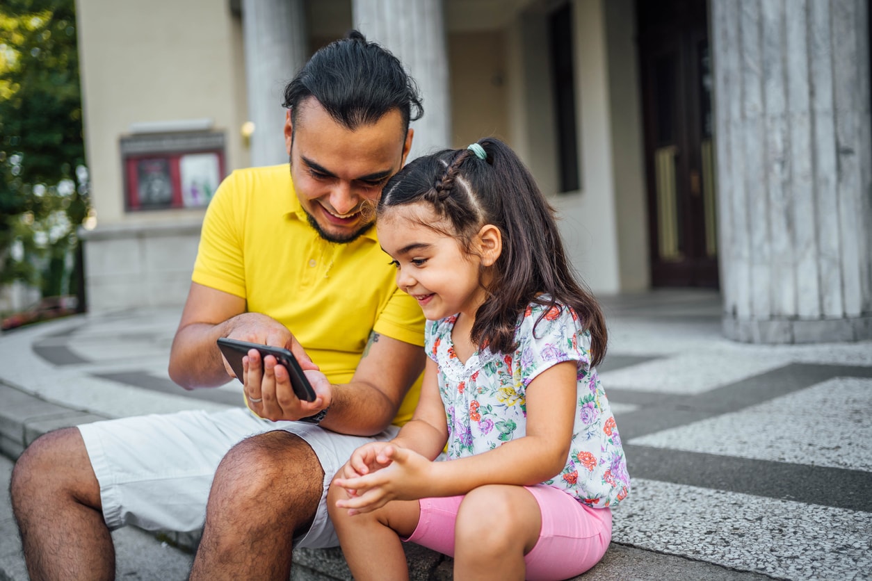Father and daughter looking at a cell phone. 