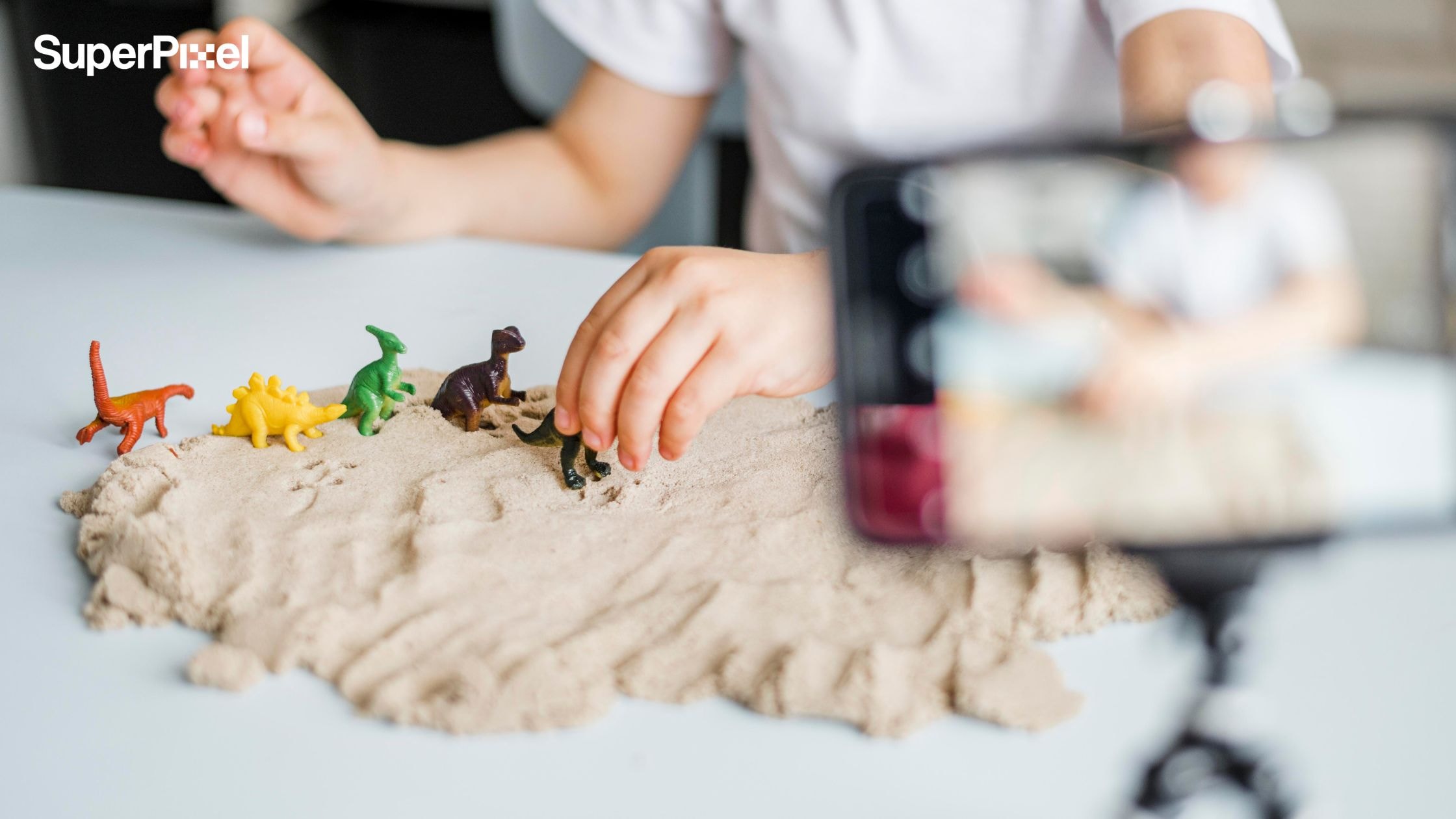 Close-up view of a young boy positioning dinosaur models frame-by-frame for stop motion. (dok.freepik)