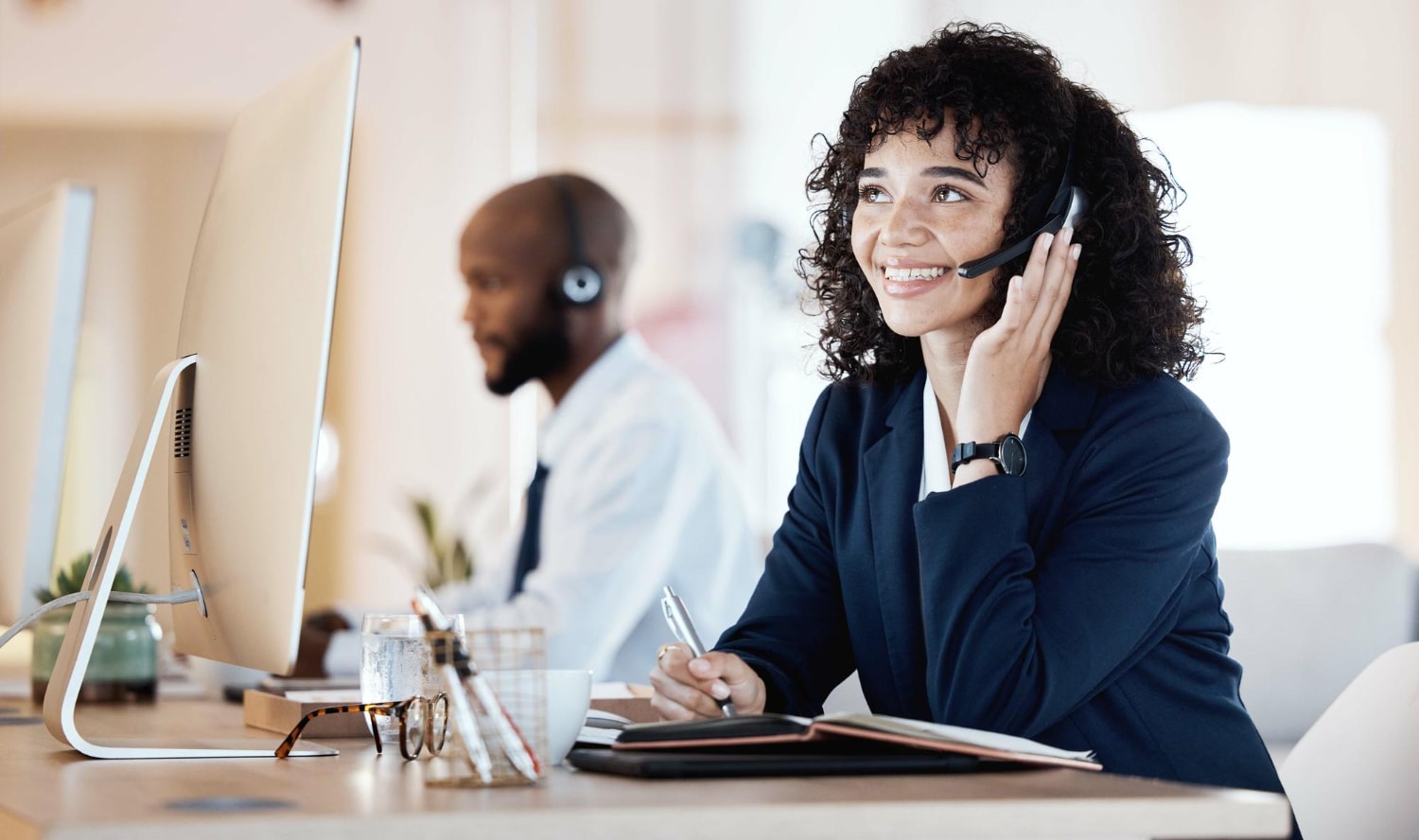 Call center professional uses a modern, easy-to-use phone system at her desk, representing streamlined phone solutions and affordable communication for business success.