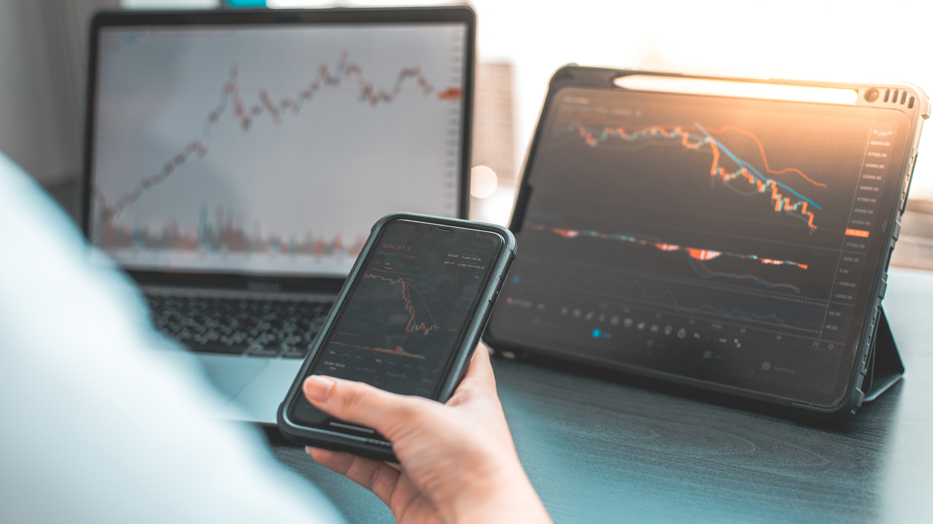 A person looking at a laptop with a stock chart and making notes