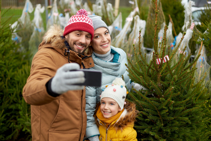 Cute family of three bundled up and smiling for a selfie.