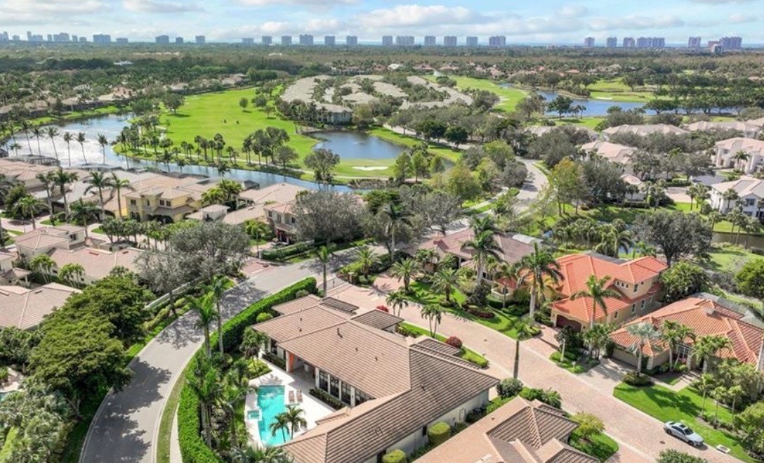 The image depicts a modern condominium community in North Naples, featuring resort-style amenities such as a community pool, tennis courts, and lush landscaping. Residents can enjoy outdoor dining and easy access to the Pelican Marsh Golf Club, making it an ideal location for those seeking a vibrant lifestyle in Naples, Florida.