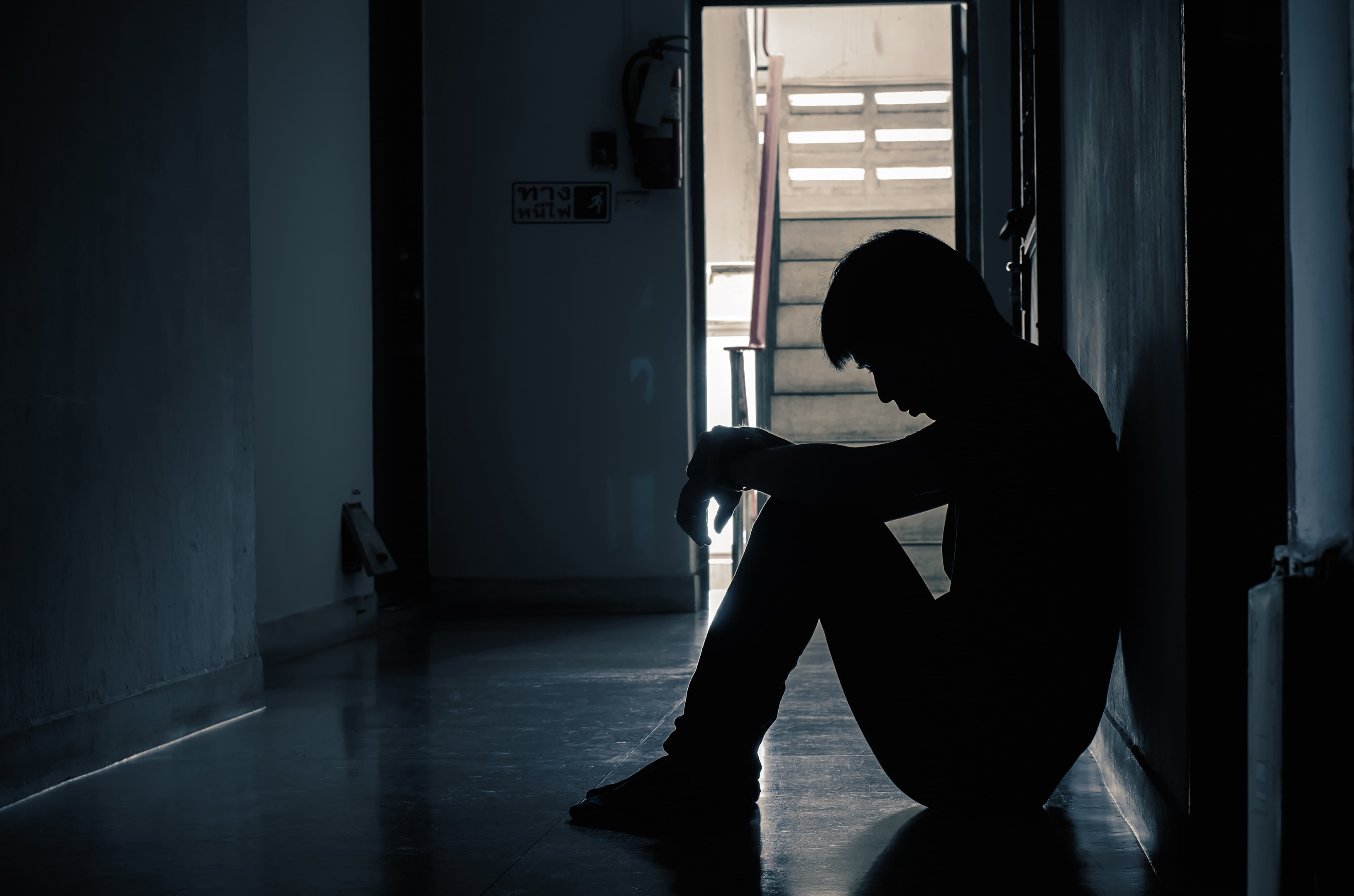 A man sitting by himself with his feelings and no one to talk to. It's pitch black and he is sitting on the floor.