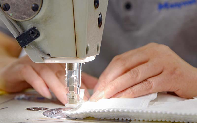 Manywell employees hand-stitching microfiber towel edges