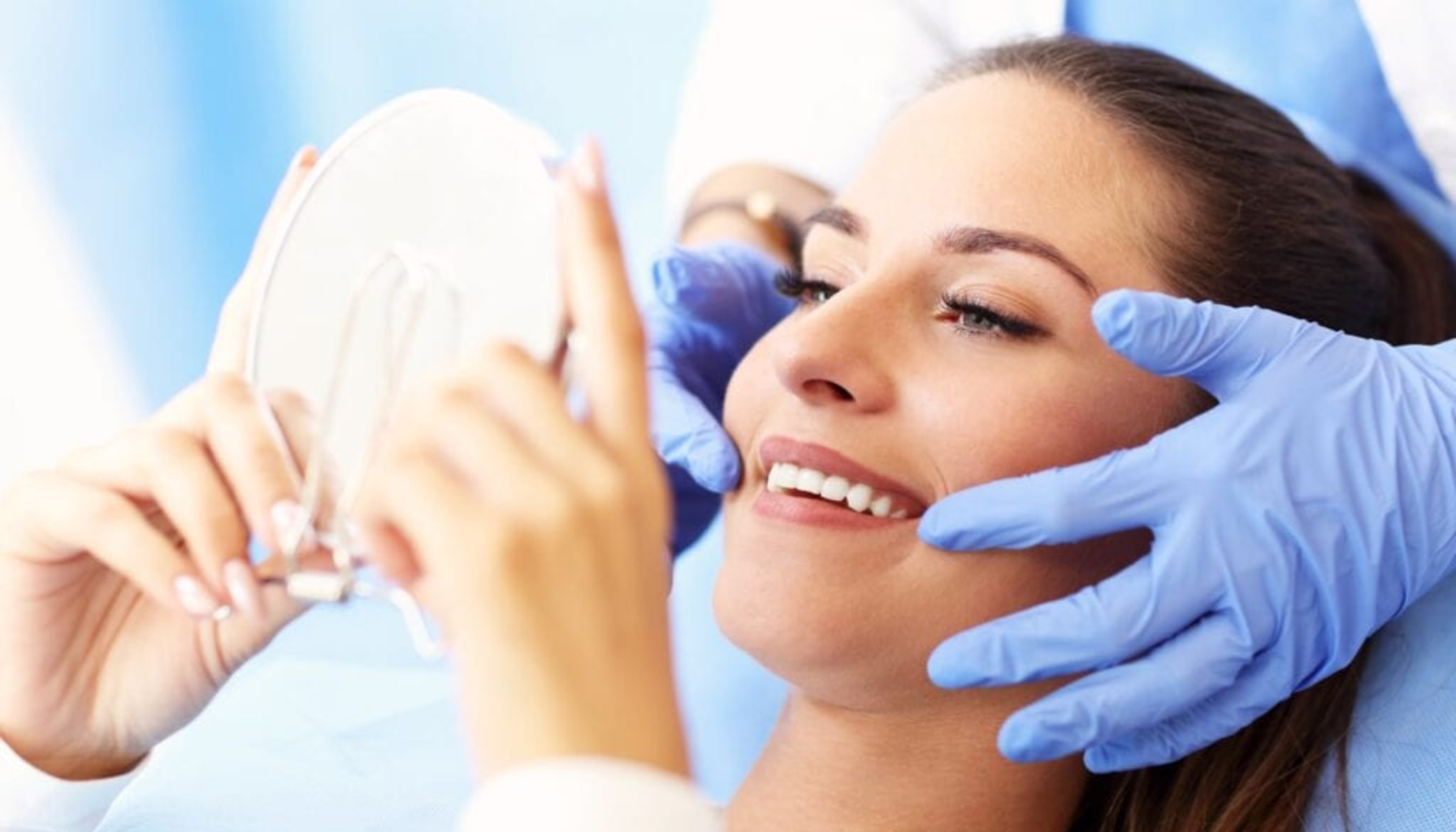 Kvinne smiler i tannlegestolen mens tannlegen med blå hansker undersøker ansiktet hennes.