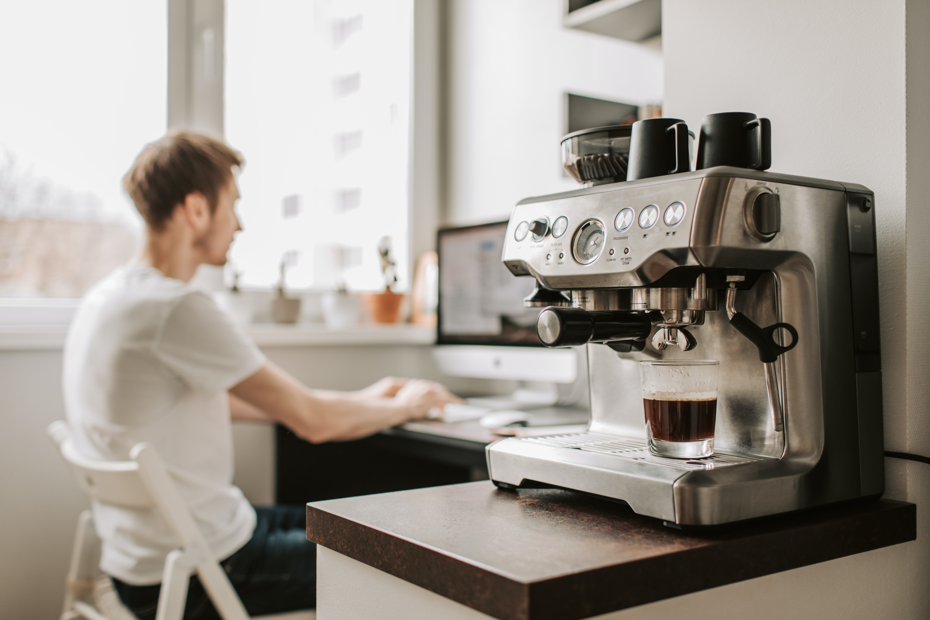 Man working from home with an espresso machine on his corner table