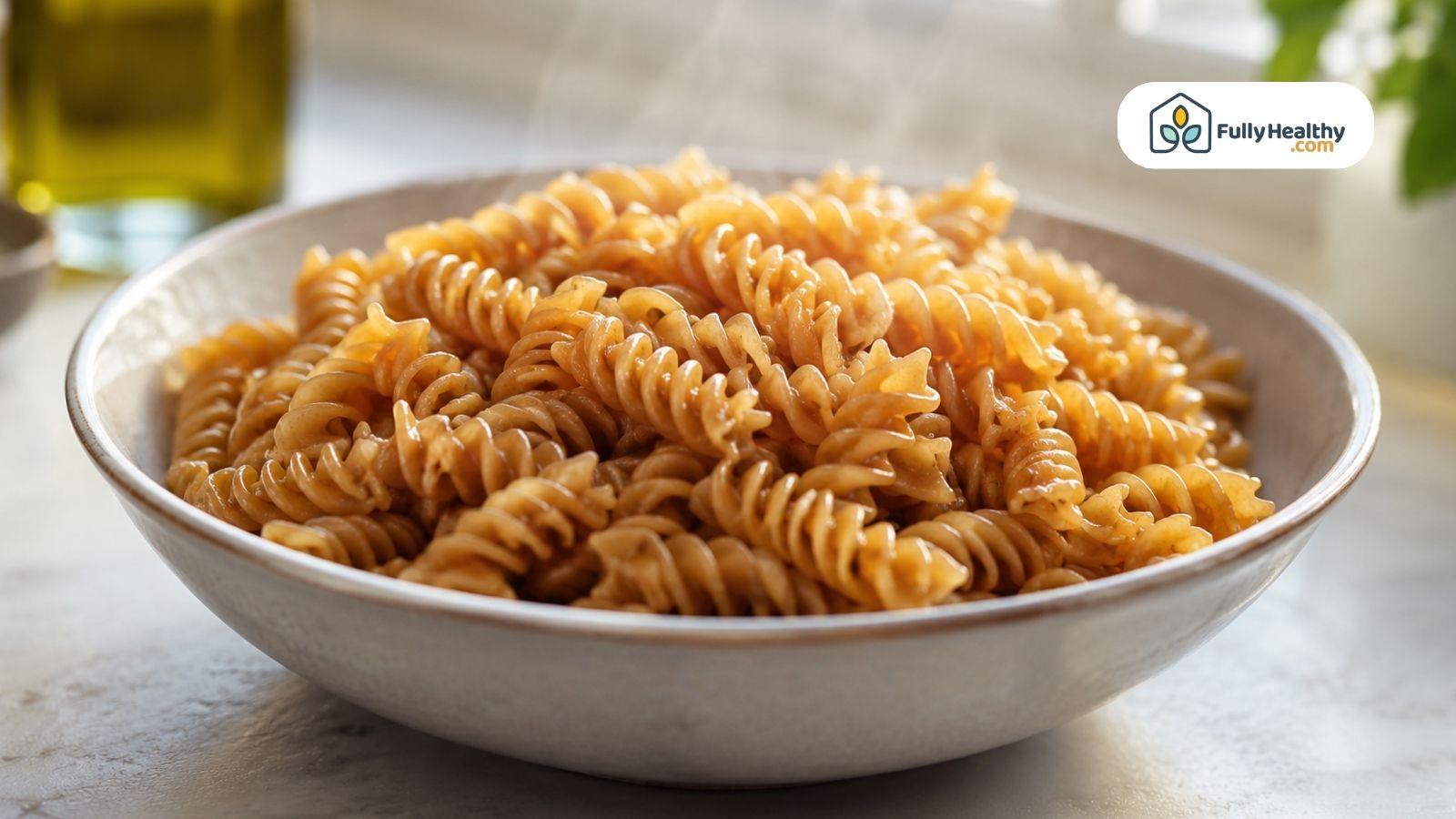 Bowl of cooked whole wheat fusilli pasta served plain in a ceramic bowl.