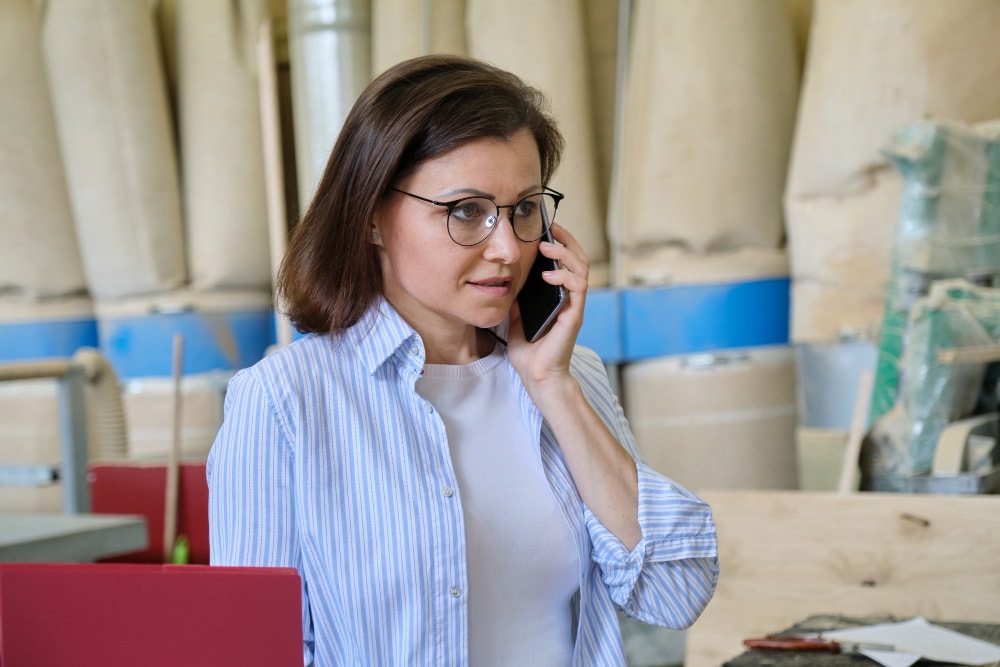 A businesswoman talking on smartphone trying to reduce telecom costs across multiple bills.