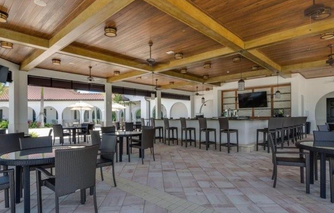 The image depicts the massive town center of Arborwood Preserve in Fort Myers, showcasing a vibrant community clubhouse that serves as a hub for entertainment and social activities, complete with amenities like a resort-style pool and fitness center. Residents can enjoy various recreational facilities, including tennis and pickleball courts, making it a perfect place for families and groups to gather and engage in events.