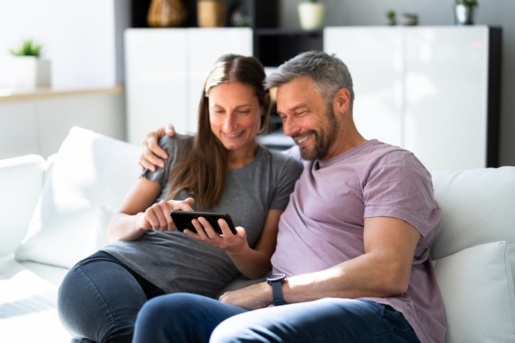 Couple sitting on the sofa looking at a cell phone. 