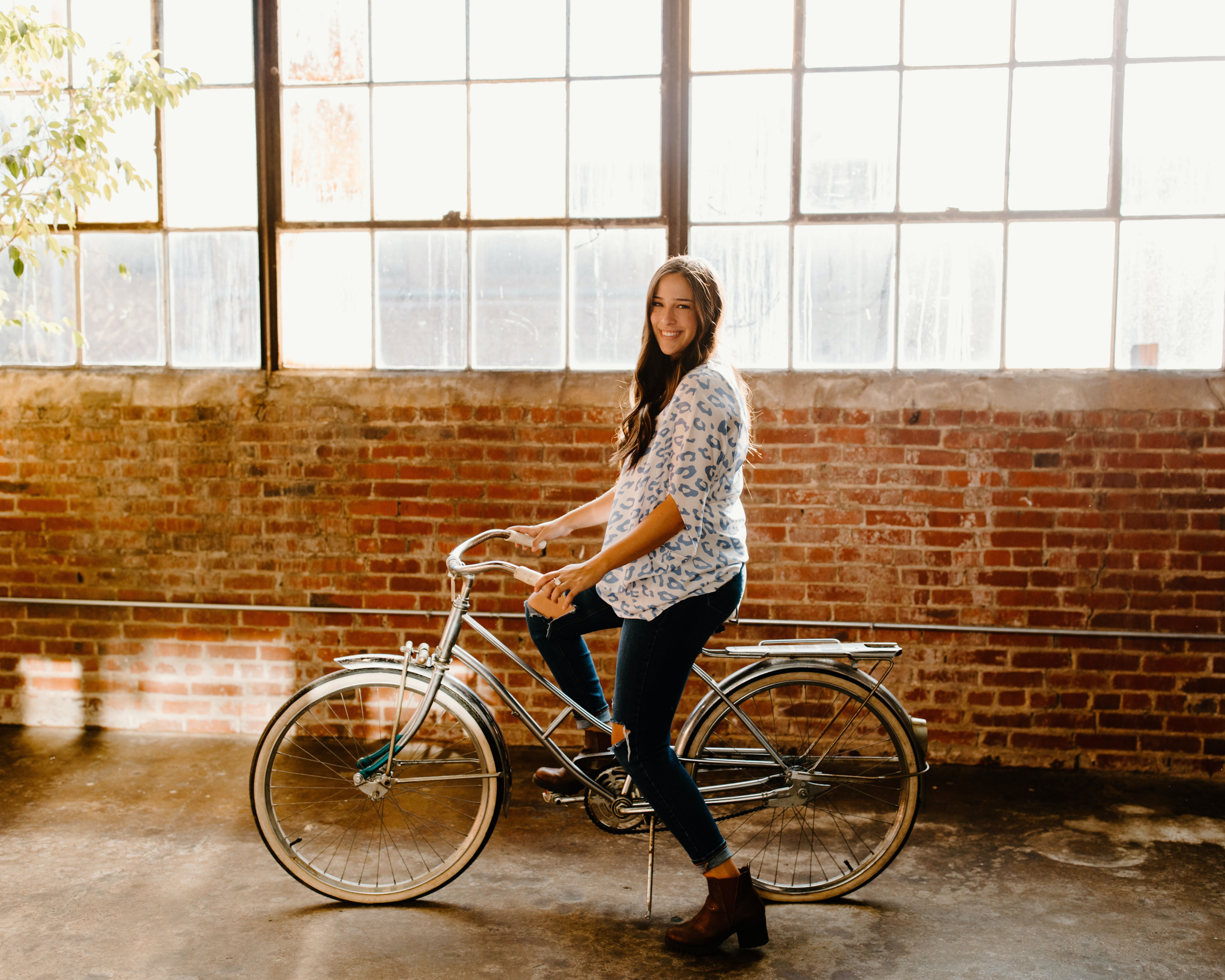 Mulher sorrindo na sua bicicleta. Foto de Hannah Busing, Unsplash