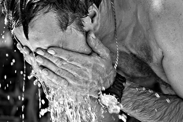 A man washing his face with water during summer heat.