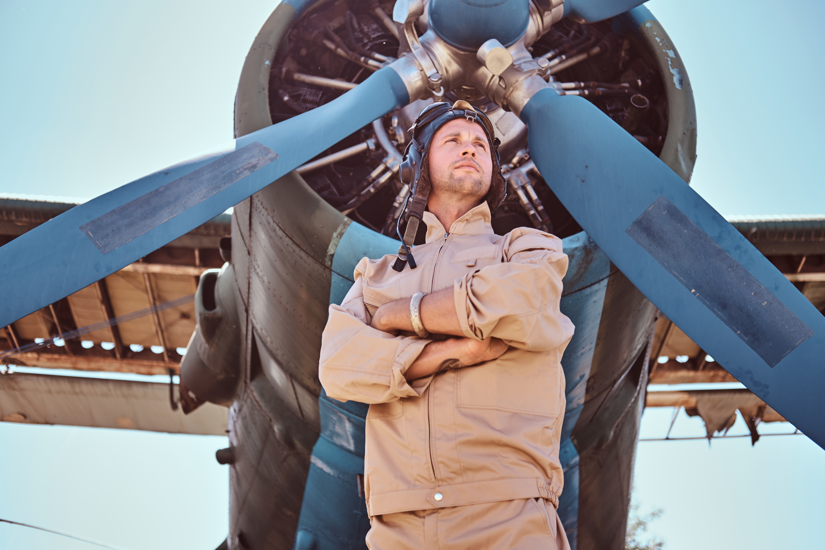 A private pilot certificate holder in a flight suit standing in front of a plane