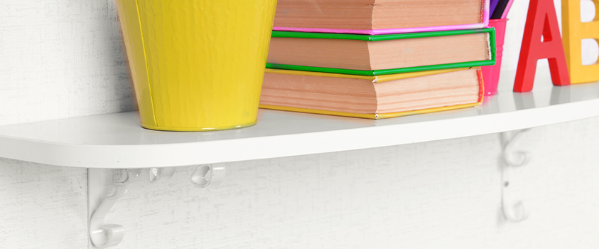 A white plastic shelf holding colourful books, buckets, and alphabet decor.