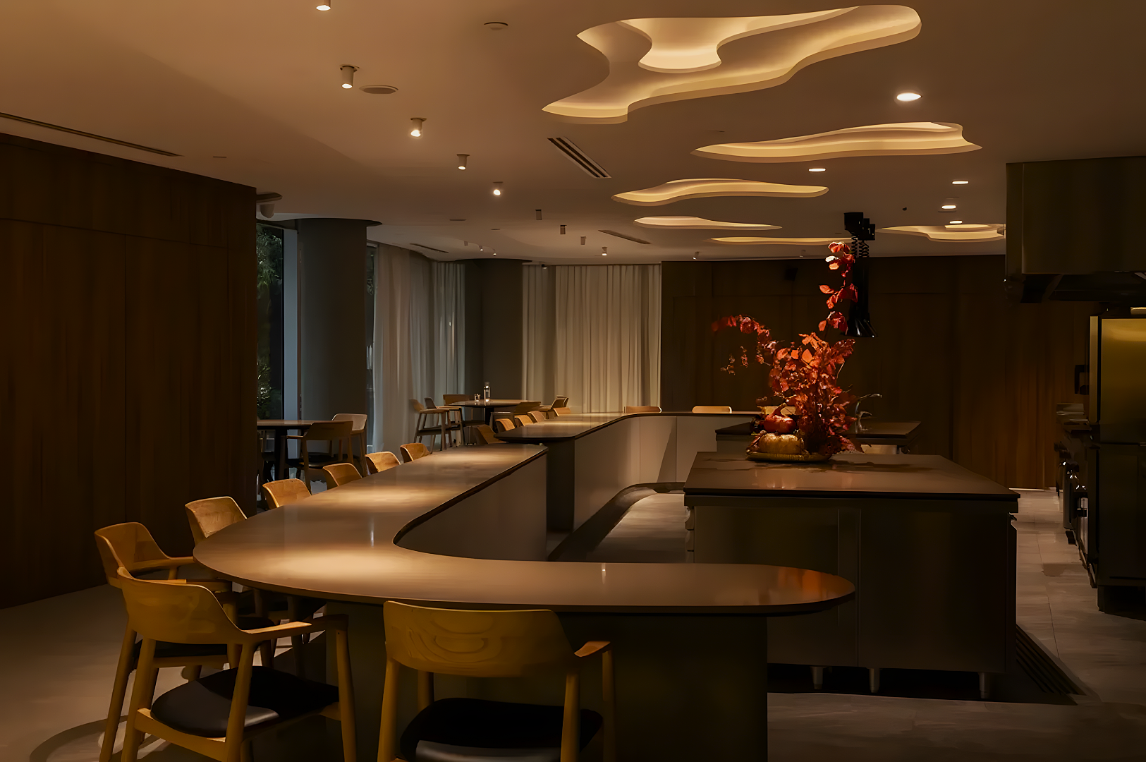 Modern kitchen with curved counters, wooden chairs, organic ceiling lights, and a decorative floral arrangement. Warm, inviting ambiance.