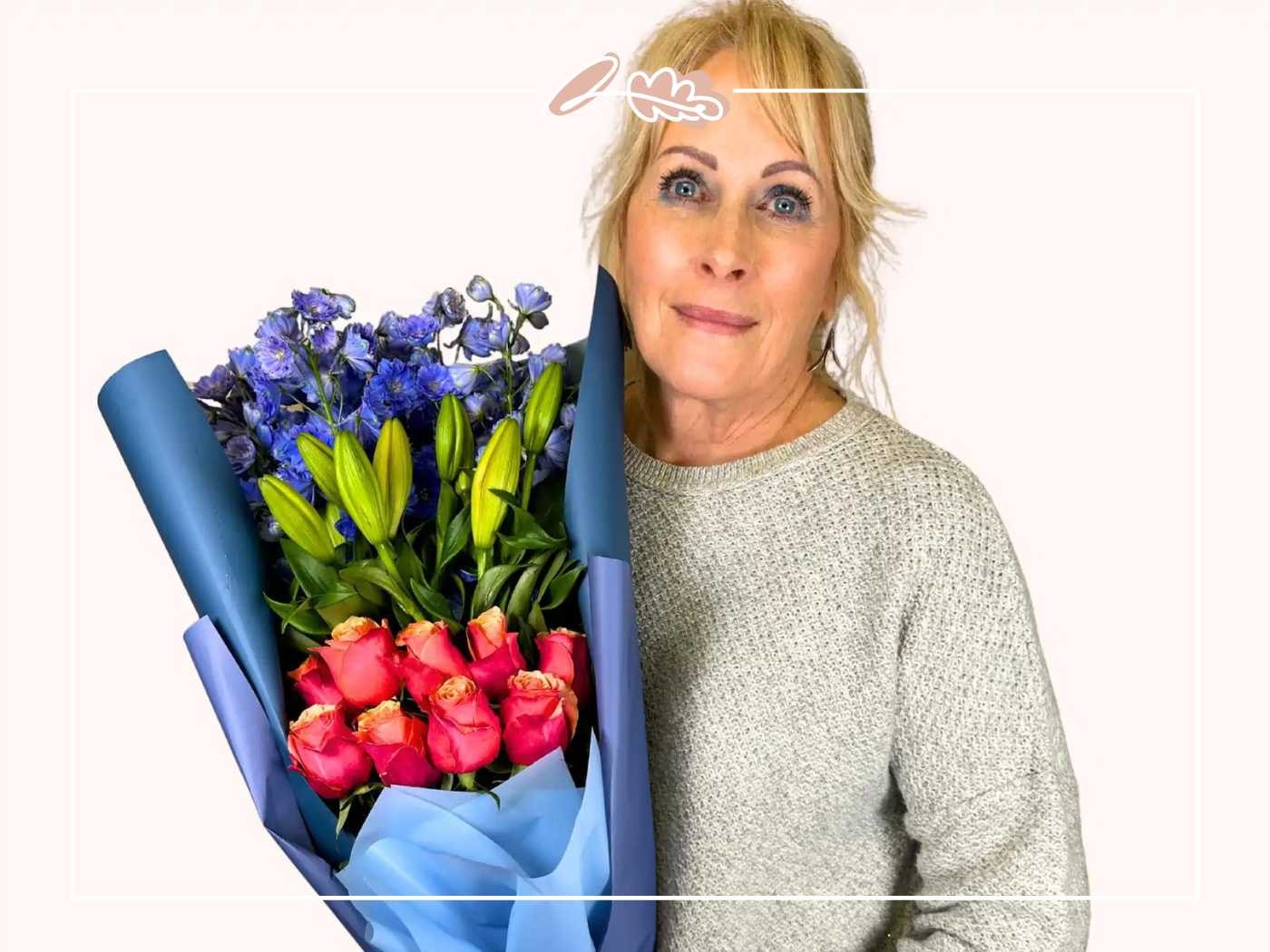 Woman holding a bouquet of blue and pink flowers by Fabulous Flowers and Gifts