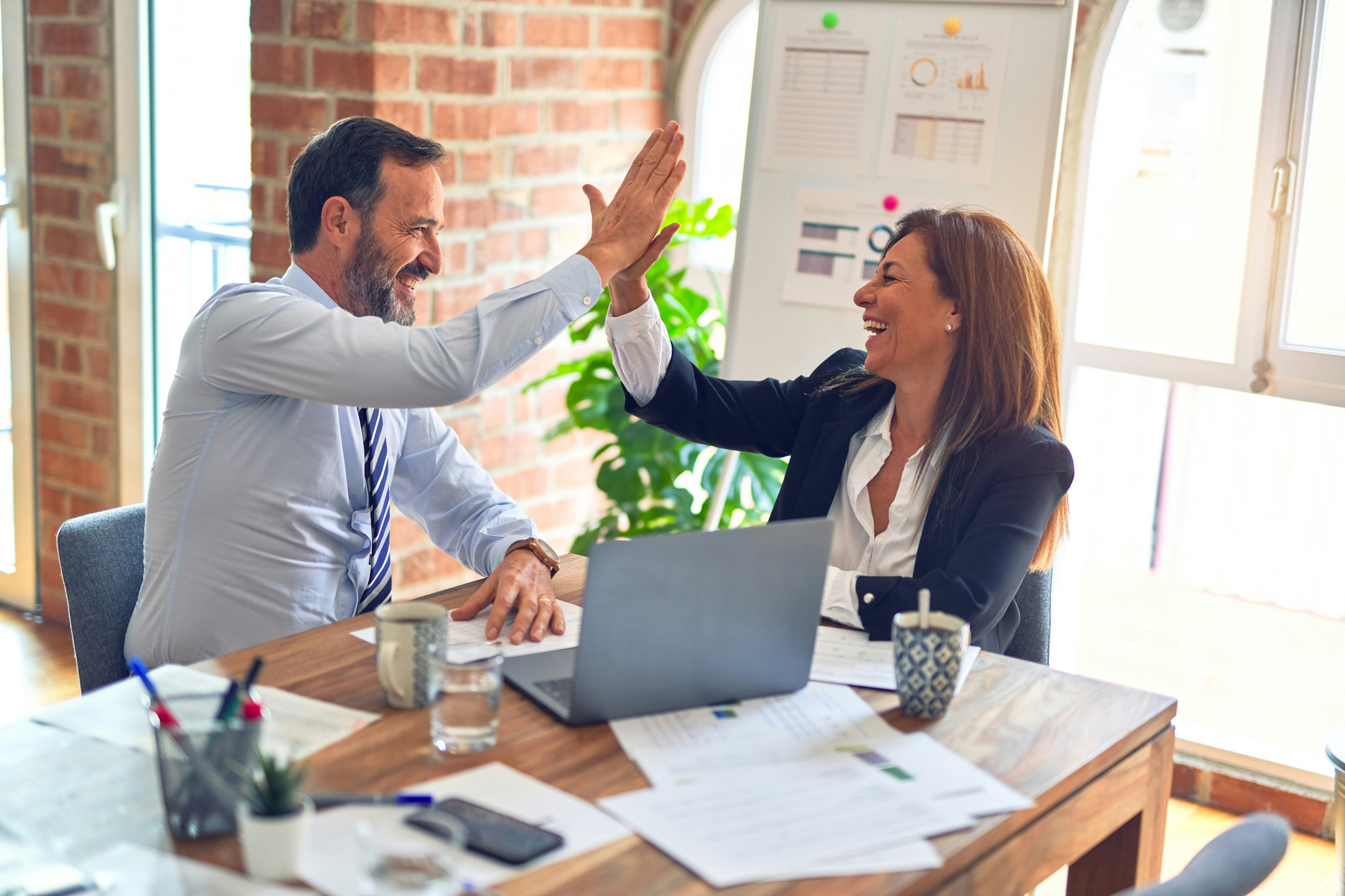Real estate investor team high fives after successful deal is closed. 