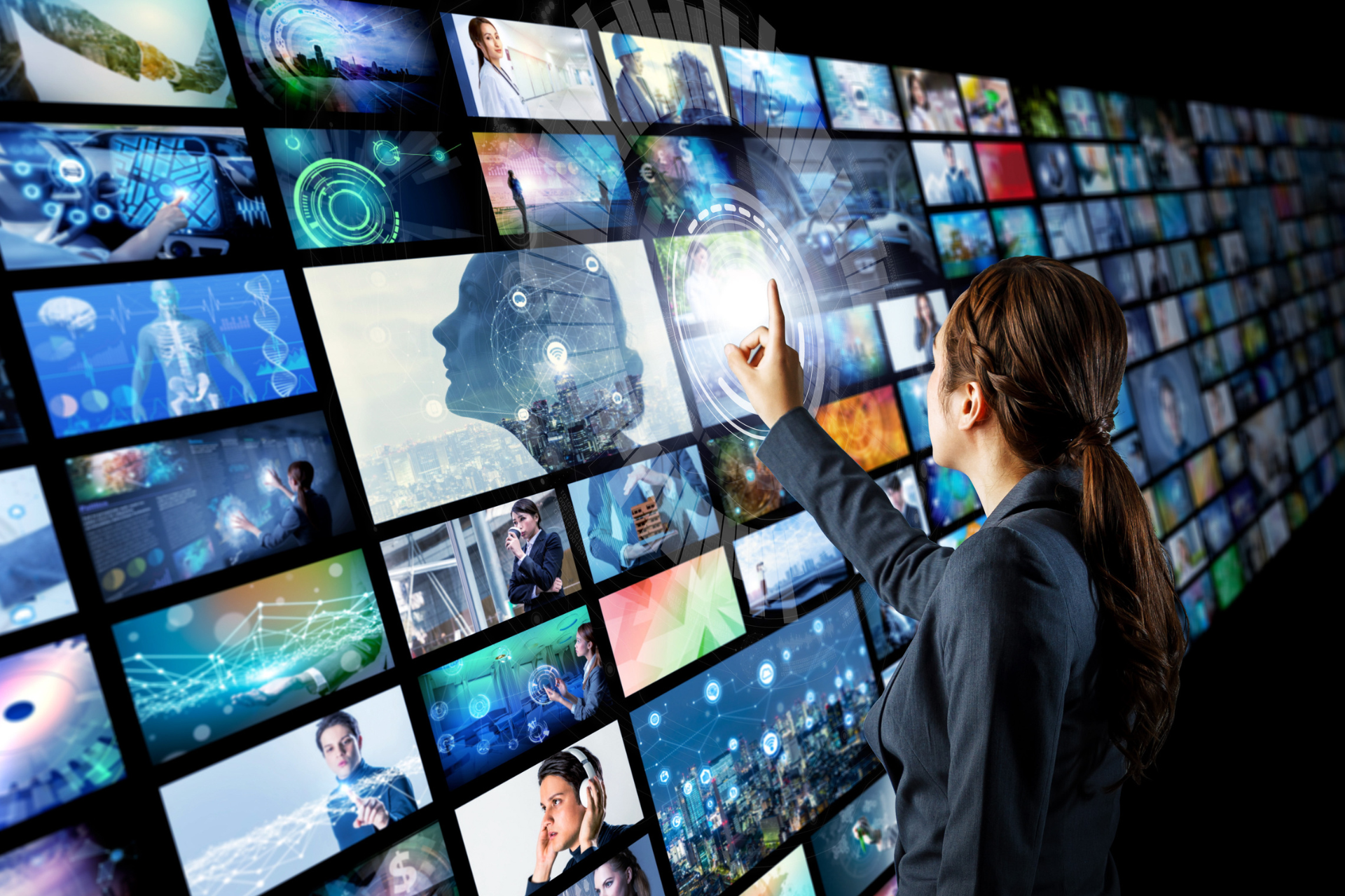 A businesswoman touching a glowing digital interface on a large wall of screens displaying diverse video content and AI imagery.