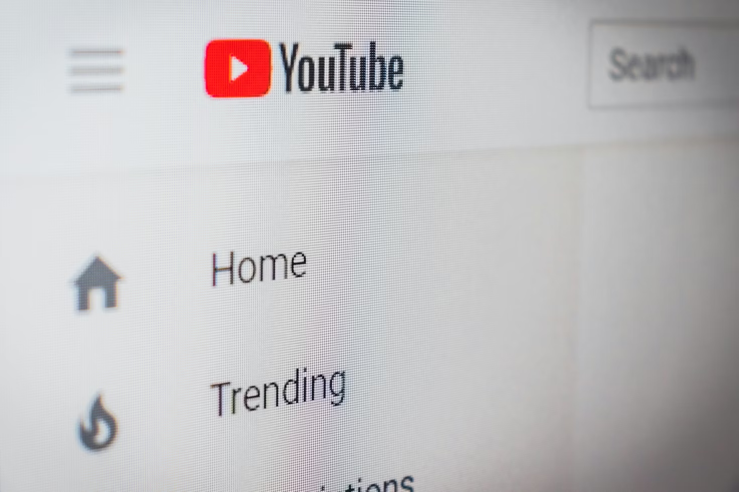 Close-up of the YouTube homepage interface showing the YouTube logo and left sidebar menu with Home and Trending icons.