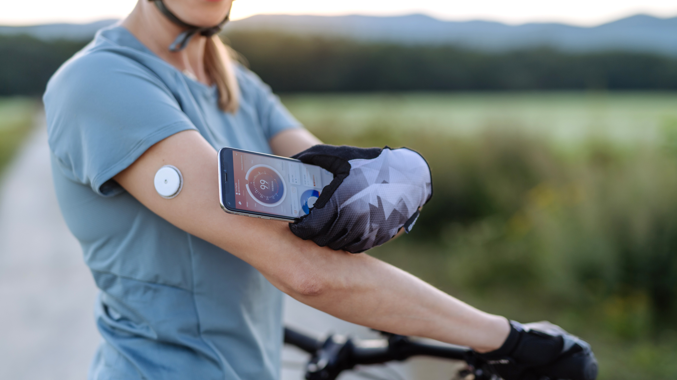 woman on bicycle using CGM device to track blood sugar levels during workout