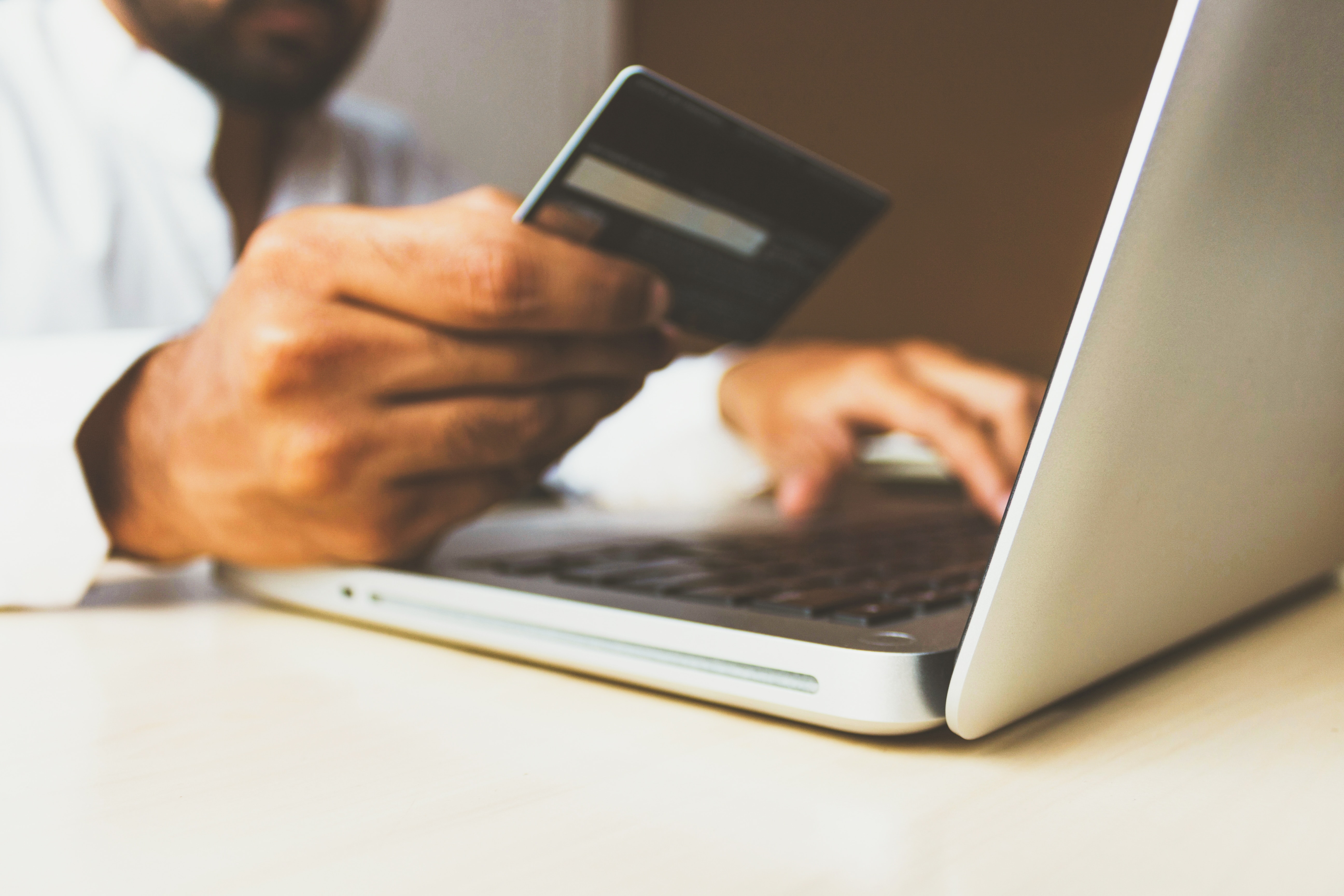 Egy férfi online vásárol egy laptopon a bankártyája segítségével