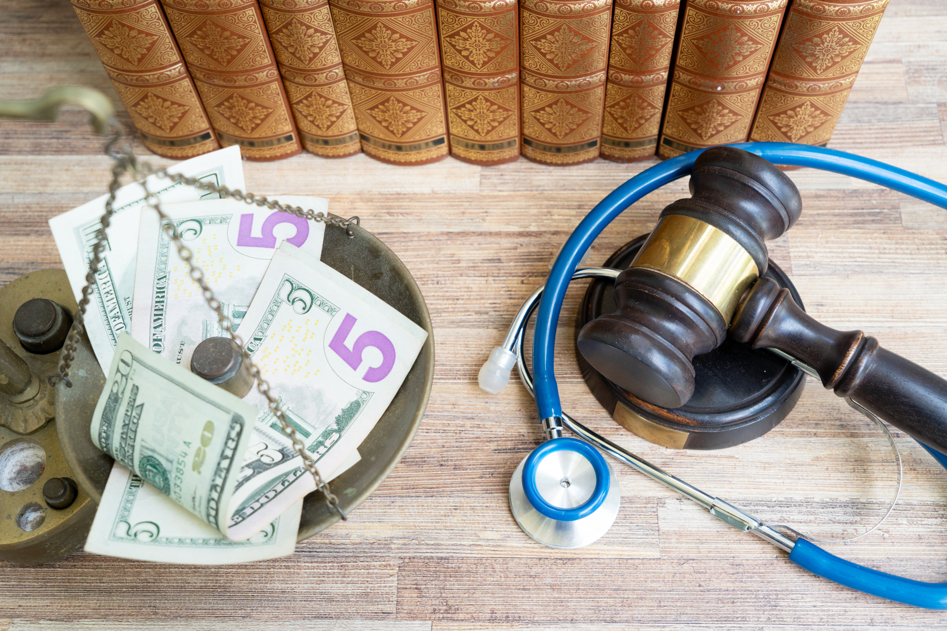 Medical Malpractice Financial concept - Gavel and Stethoscope on a table next to a scale with money on it. 